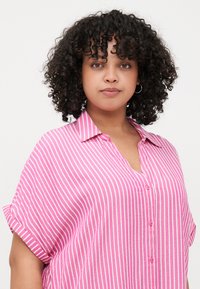 Pink and white striped button-up shirt with a collar, short rolled sleeves, and a relaxed fit. Made of a lightweight fabric with a soft texture.
