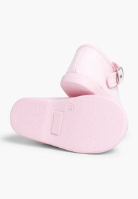 Scarpa in tessuto rosa con punta arrotondata, cinturino regolabile con fibbia in metallo e suola in gomma con motivo testurizzato.