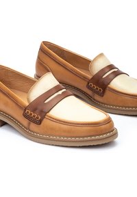 Mocasines de cuero marrón con un empeine de cuero crema, correa marrón en contraste, costuras blancas y puntera redondeada. Suelas planas.