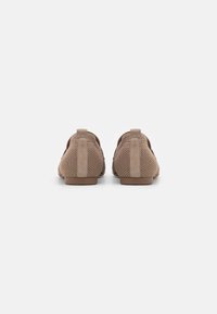 Mocasines de malla marrones con acentos de ante, perfil bajo, tacón redondeado y detalle texturizado en la parte posterior. Diseñados para un uso casual y comodidad.