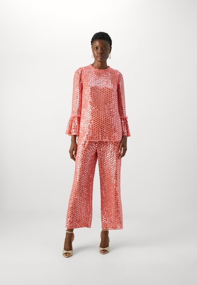 Shiny pink sequined top with ruffled sleeves paired with matching sequined pants; both feature a loose, flowing fit and round neckline.