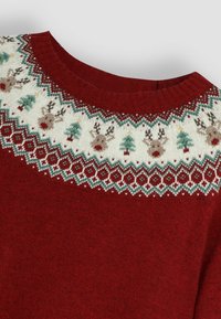 Pulover de Crăciun roșu, cu guler rotund, cu un model complex de tricot în alb, verde și maron, cu reni și brazi de-a lungul umerilor.