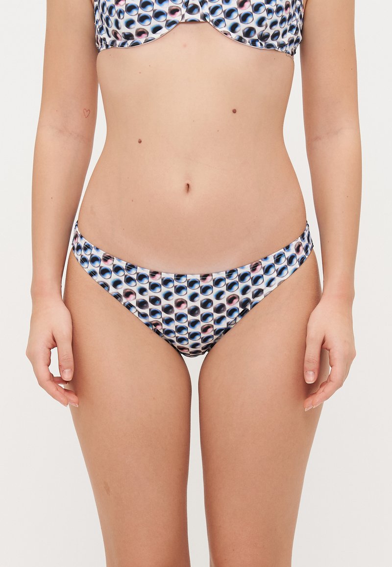 Bikini komplekts, kas sastāv no topa ar veidotiem krūšu ieliktņiem un atbilstošām zemu piegriezumu biksītēm, abiem ar zila un balta acs raksta dizainu, izgatavots no gludas auduma.