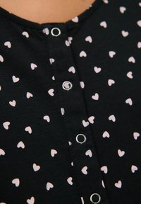 Črna tkanina s pink vzorcem srčkov, z okroglim izrezom in gumbom s srebrnim kovinskim detajlom. Prijetna, lahka zasnova.