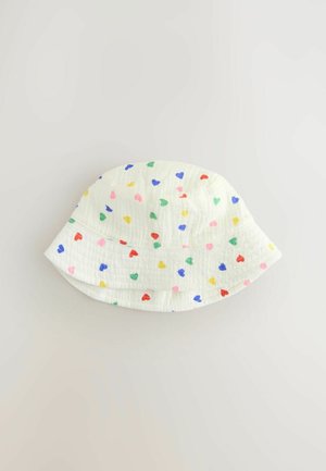 Balts spaiņcepure no teksturētas auduma, ar daudzkrāsainu sirds rakstu sarkanā, rozā, zaļā, zilā un dzeltenā krāsā.