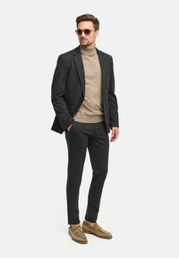 Kullgrå dress med en fitted blazer, lys beige turtleneck og beige loafers. Inkluderer solbriller, glatt stoff og skreddersydd design.