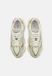Grønne og kremfargede sneakers med mesh- og semsket skinnmaterialer, med et kraftig design, teksturerte paneler og hvite snørebånd.