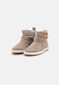 Botine gri din suede cu un interior moale alb, vârf rotund și o curea laterală cu un accent de piele maro. Talpă din cauciuc alb.