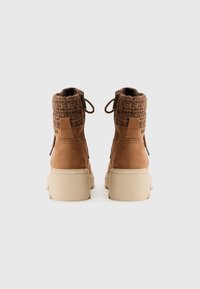 Bottes de cheville en cuir suédé marron avec un col en maille texturée, accentuées par une semelle épaisse beige et des languettes pour un enfilage facile.