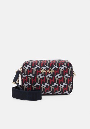 Sac bandoulière rectangulaire avec un motif répétitif "TH" en rouge, blanc et beige, logo doré "Tommy Hilfiger" et bandoulière amovible bleu marine avec marquage embossé.