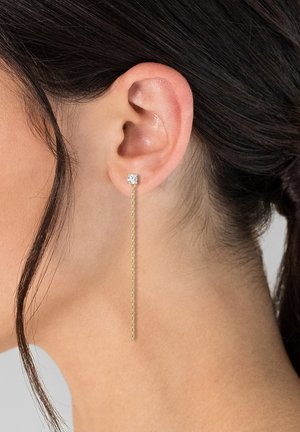 Ohrringe aus goldenen Ketten mit langem Anhänger, die einen klaren Zirkonia-Stecker am Ohrläppchen haben. Die Kettenstruktur ist glatt und zart.