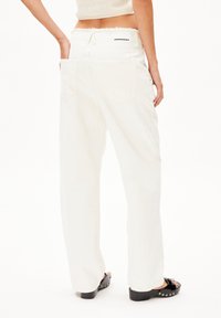 Witte, losse broek met een rafelige taille, twee achterzakken en een logotag. Glad, zacht stof met een lichte glans en rechte pijpen.