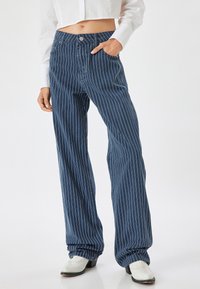 Jeans de pierna ancha azul a rayas con un cinturón de botones y bolsillos delanteros, que presentan una textura de mezclilla suave y un ajuste relajado.
