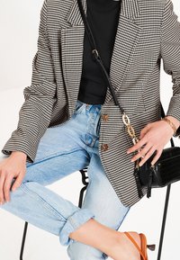 Černobílý kostkovaný blazer, černý top, světle modré džíny, oranžové sandály, černá kabelka, vyhrnuté džíny, zlaté doplňky.