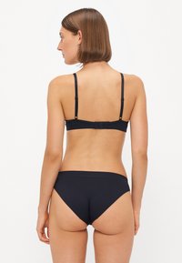 Zwart bh- en bikini-set van glad, rekbaar materiaal, met verstelbare bandjes en naadloze randen voor comfort en een minimalistische uitstraling.