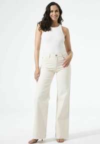 High-waisted, wijde broekspijpen in gebroken wit denim. Voorzien van een klassiek ontwerp met vijf zakken, knoopsluiting en een subtiele textuur.