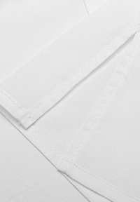 White fabric with crisp folds and seams, featuring a smooth texture. Stitching visible along edges, highlighting careful craftsmanship.