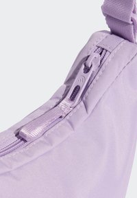 Borsa in tessuto lilla con una superficie liscia, dotata di chiusura con cerniera e tirazip in plastica resistente. La tracolla è regolabile e coordinata nel colore.