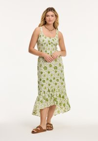 Bloemen midi-jurk in groen en wit, met een aansluitende bodice, uitlopendezoom en ietsjes gerimpelde rok. Draag met bruine platte sandalen.
