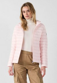 Roze pufferjack met capuchon, voorzien van horizontale doorgestikte secties, een rits aan de voorkant en een slank ontwerp. Gedragen over een crèmekleurige coltrui.