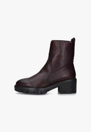 Stivale alla caviglia in pelle marrone con punta rotonda, dettaglio cucitura laterale e tacco spesso nero. Presenta un manico sul retro per facilitare l'indossamento.