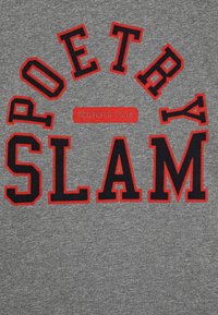 Szara koszulka z dużym haftowanym napisem: "POETRY SLAM" w kolorze czarnym i czerwonym. Na środku mniejsza czerwona czcionka z logo marki "SCOTCH & SODA".
