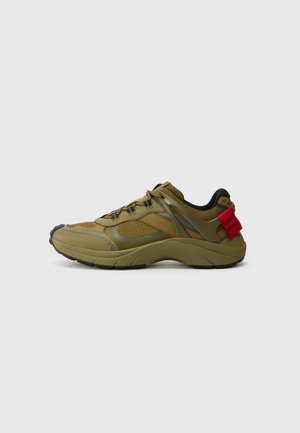 Dark green athletic shoe with mesh and synthetic material, featuring grey accents, textured midsole, and a prominent red logo tag at the heel.