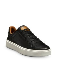 Baskets en cuir noir avec un panneau latéral perforé, accent en cuir tan sur la languette et une semelle en caoutchouc blanche épaisse. Conception à lacets.