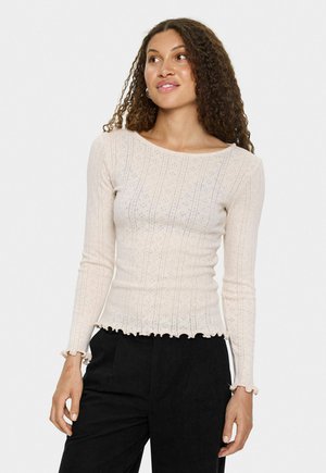 Top de manga larga beige claro con patrón acanalado, diseño de puntos sutil y dobladillo con forma de concha. Fabricado con tela suave, con silueta ajustada.