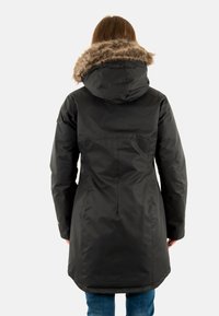 Parka noire isolée avec une capuche doublée de fausse fourrure, présentant une coupe droite et des manches longues, atteignant mi-thigh avec une texture lisse.