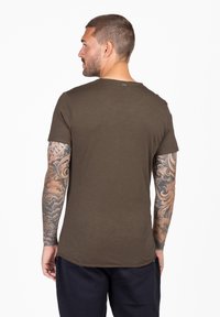 T-shirt a maniche corte verde oliva scuro con scollatura rotonda, caratterizzato da un orlo curvo e un piccolo marchio sul retro.