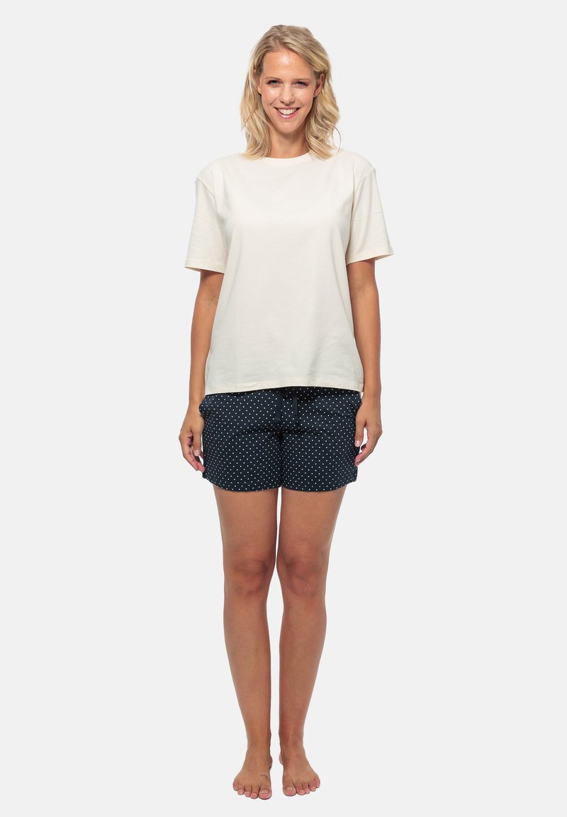 Lässiges Outfit mit einem locker sitzenden, crèmefarbenen Baumwoll-T-Shirt und dunkelblauen Shorts mit weißen Punkten, elastischem Bund und seitlichen Taschen.