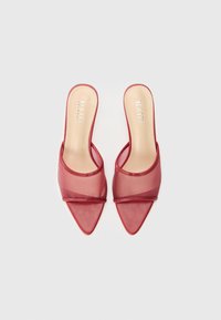 Red heeled mules with a sheer mesh upper and pointed toe. Features a slim band across the top and a smooth, light-colored insole.