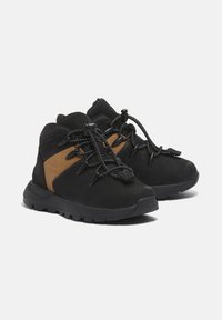 Černé a hnědé střední turistické boty s texturovaným svrškem, zajištěnou šněrovací systémem a gumovou podrážkou pro přilnavost a odolnost.
