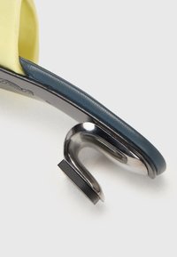 Sárga textil felsőrész, tengerészkék ívelt pánttal. Ezüst színű fémbakra épülő, négyzet alapú sarokkal rendelkezik. Sima tapintású; minimalista design.