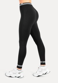 Svarta leggings med hög midjeresår som har en vit randig detalj. Materialet är slätt och stretchigt, designat för komfort under aktivitet.