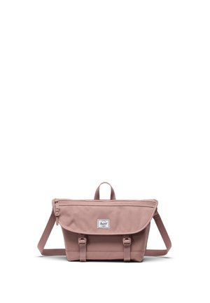 Støvet lyserød Herschel crossbody taske med frontklap, justerbar rem og to spænde lukninger på hvid baggrund.