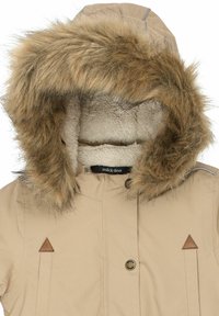 Beige Jacke mit kapuzenbesatz aus Fell, die ein weiches, strukturiertes Innenfutter, Knopfverschluss und dreieckige Lederakzente aufweist.