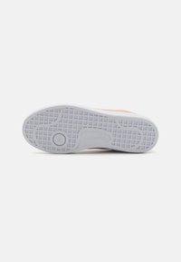 Baskets Lacoste avec une semelle en caoutchouc blanc texturé à motif en grille, complétées par un dessus en pêche doux et un détail de logo.
