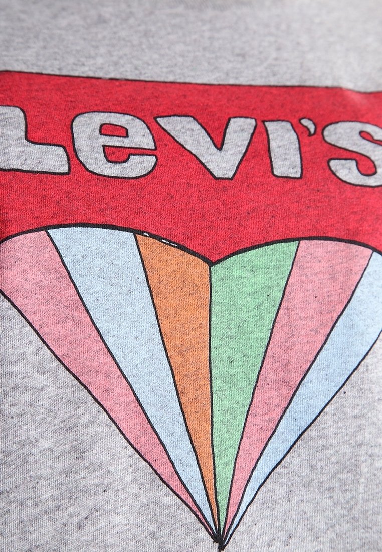 Šedé tričko s červeným logem "Levi's" nad srdcovým tvarem vytvořeným z duhově barevných pruhů v růžové, oranžové, zelené, modré a béžové.