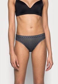 Bikini bottom a pois bianco e nero con un tessuto liscio e elastico, vita media e taglio classico per comfort e vestibilità.