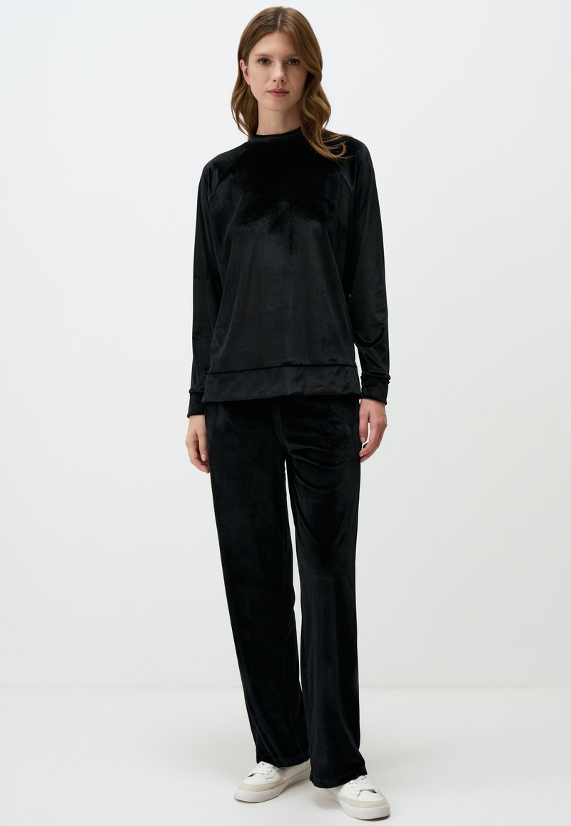 Set di abbigliamento da casa in velluto nero composto da una maglia a maniche lunghe con scollo rotondo e pantaloni dritti, entrambi con una texture liscia e morbida.