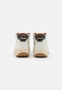 Weiße Leder High-Top Sneakers mit navyblauem Akzent, tanfarbener Wildleder-Innenausstattung und beigefarbenem strukturierten Sohle. Goldenes Logo auf der Rückseite.