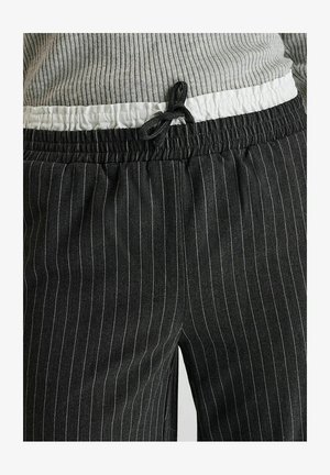 Schwarze Nadelstreifen-Hosen mit strukturierter Oberfläche; elastischer Bund mit weißem Akzent und verstellbarem Kordelzug.