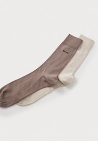 Two pairs of socks: one brown and one beige. Each sock features a ribbed cuff and a logo, made of smooth fabric with a consistent texture.