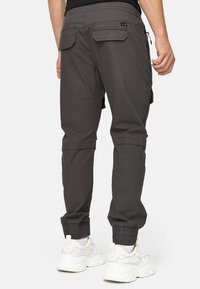 Pantalones cargo grises con perneras ajustadas, puños elásticos y múltiples bolsillos. Presentan una textura suave y un diseño práctico adecuado para el uso diario.