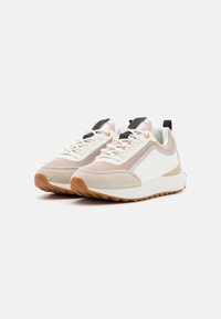 Béžovo-bílé tenisky s panely z síťoviny a semiše, černými detaily a podrážkou z gumové pryže. Mají šněrování a polstrovaný límec.