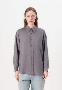 Camisa cinza de botão com riscas verticais cor-de-rosa, colarinho espalhado, bolso frontal e mangas longas. Textura suave, ajuste descontraído.