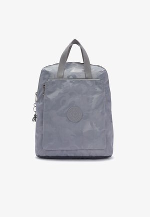 Sac à dos carré gris avec motif camouflage, poche avant zippée, deux poignées courtes et un petit porte-clés singe sur la languette de la fermeture éclair latérale.