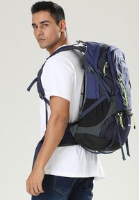 Zaino blu navy con design testurizzato, spallacci regolabili e dettagli verde neon. Presenta più scomparti e un materiale resistente.